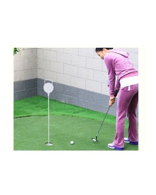 A female golfer practicing putt with putting hole cup with flagpole